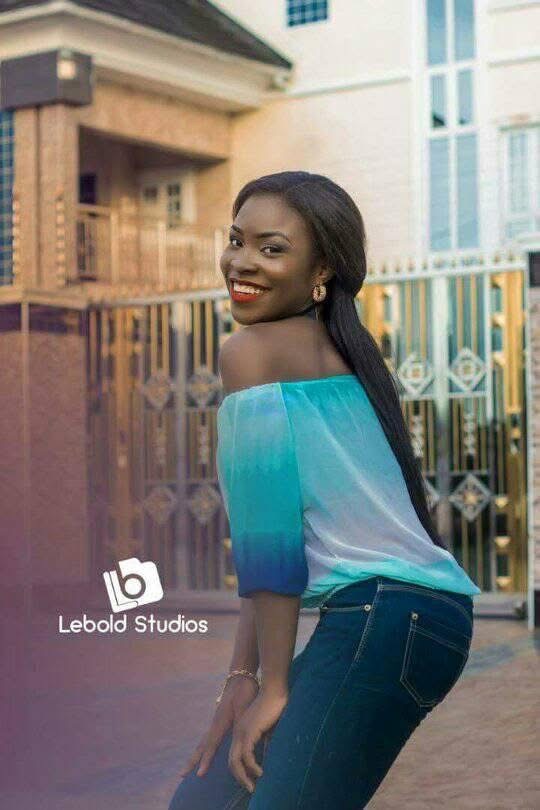 MaryAlice looking over her shoulder in a turquoise off-shoulder top in front of a gold gate